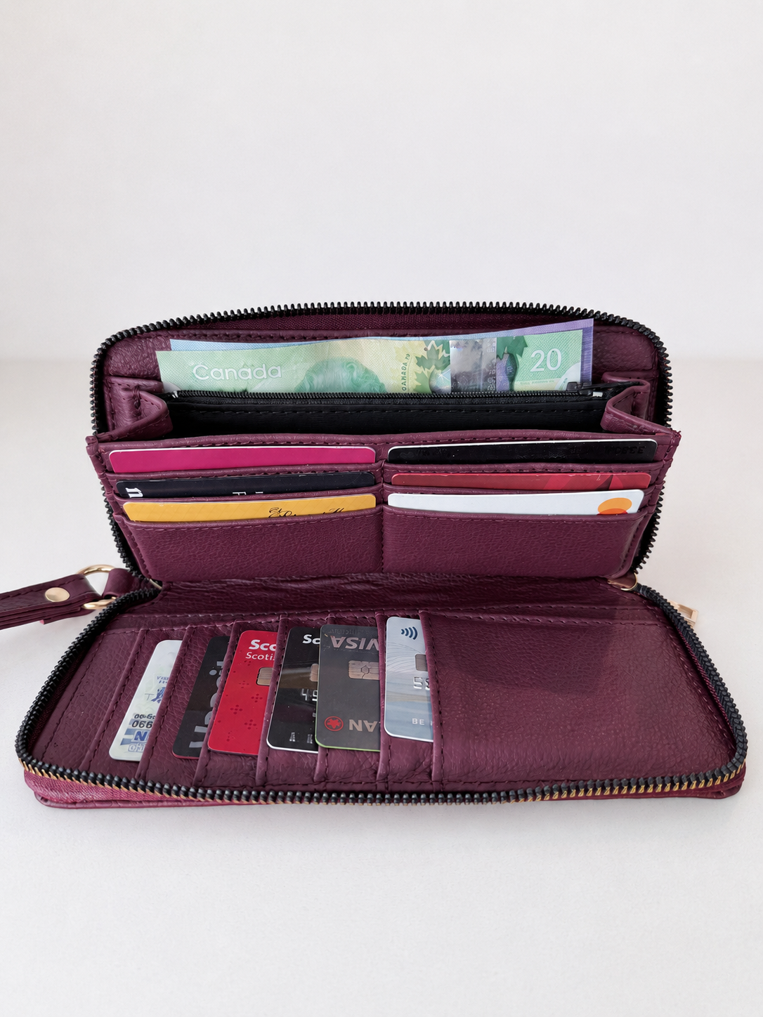 Purple wallet with various cards and money on a white background