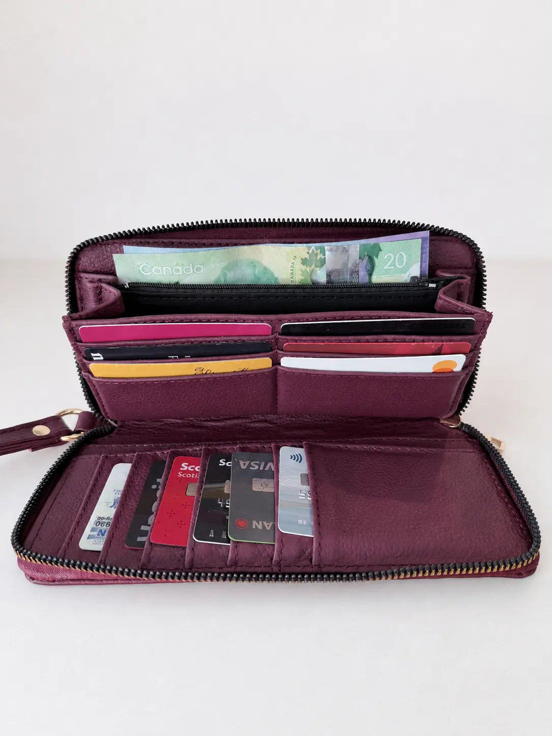 Purple wallet with various cards and money on a white background