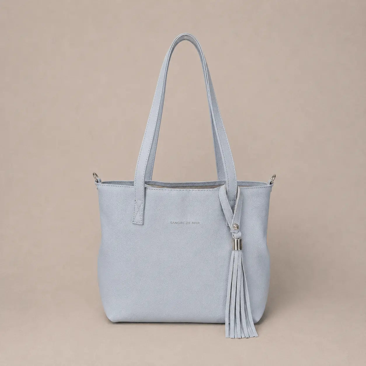 Off-white cold handbag with a tassel on a beige background