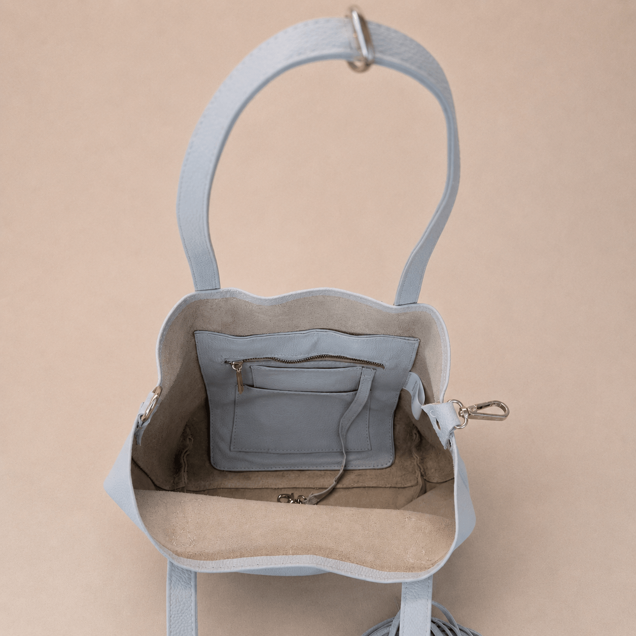 Off-white cold handbag with a tassel interior on a beige background