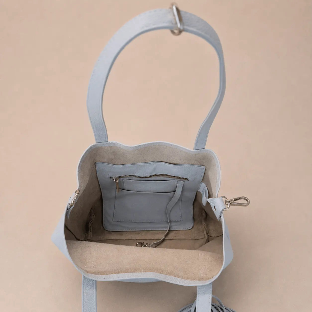 Off-white cold handbag with a tassel interior on a beige background