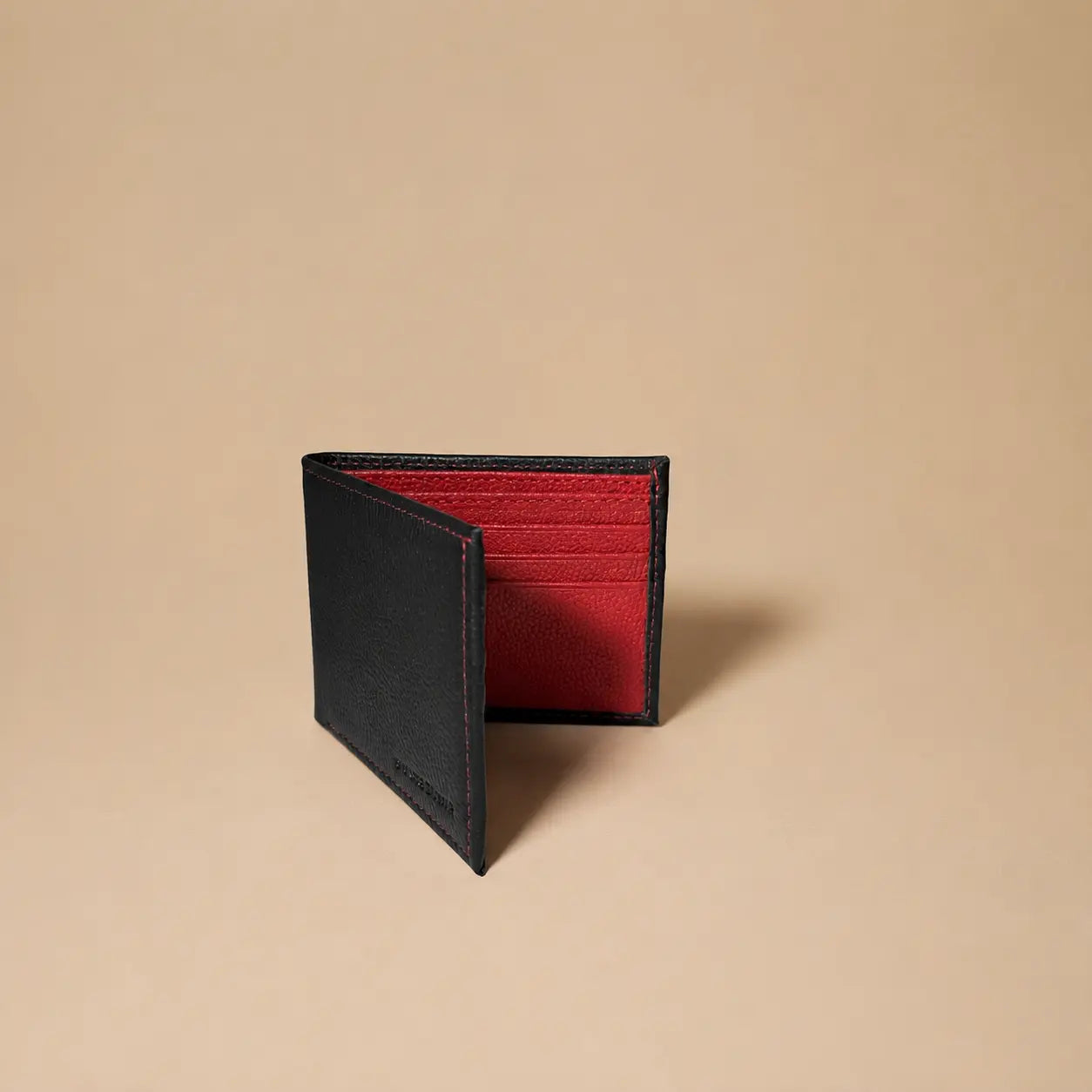 Black wallet with red interior on a beige background