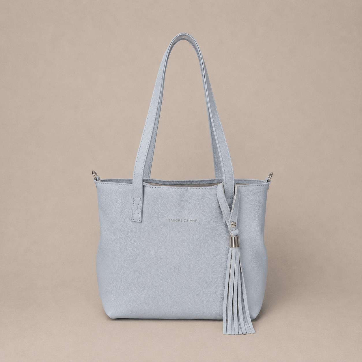 Off-white cold handbag with a tassel on a beige background