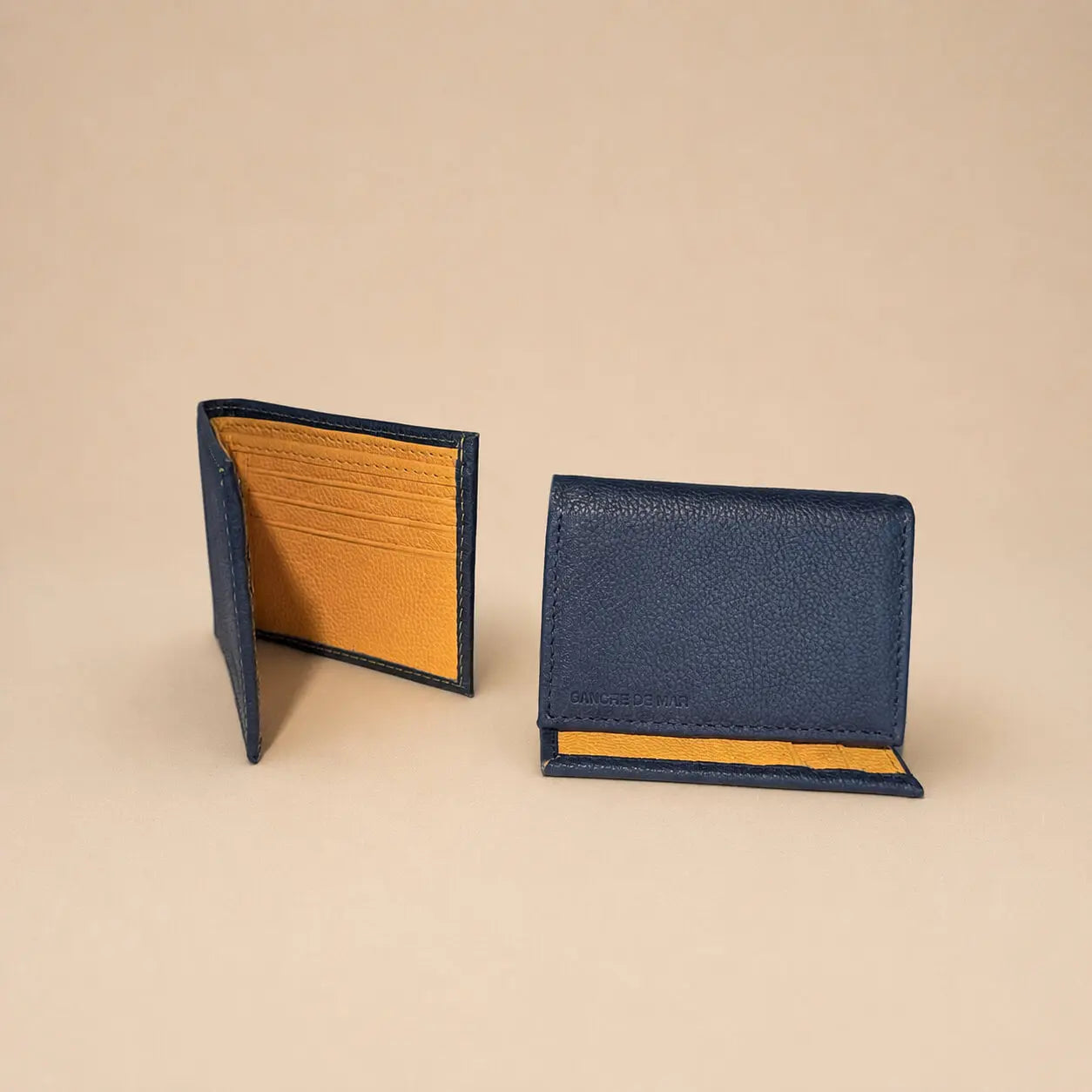 Two leather wallets, one blue and one with a textured pattern, on a beige background.