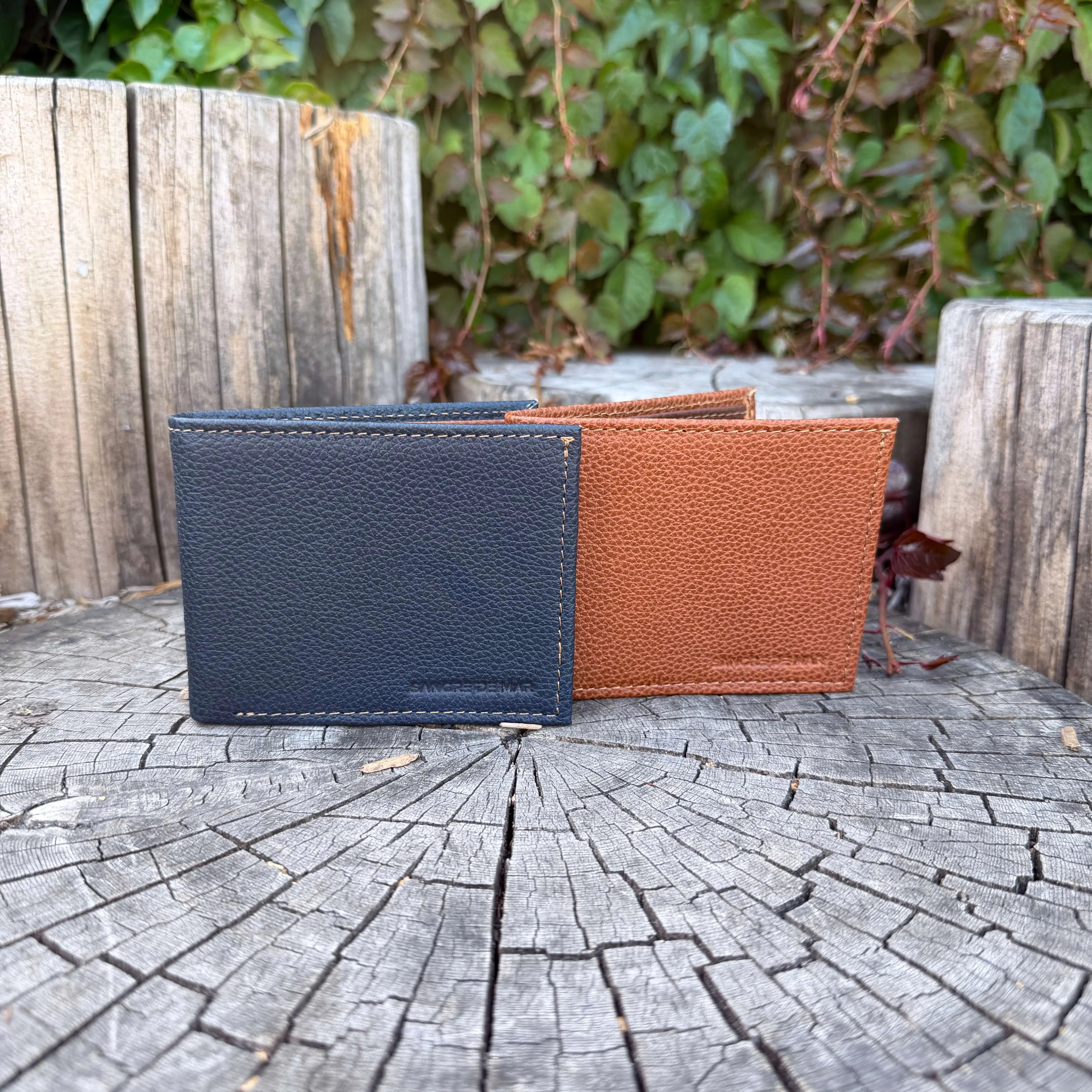 Two leather wallets, one black and one brown, on a wooden surface with a natural background.